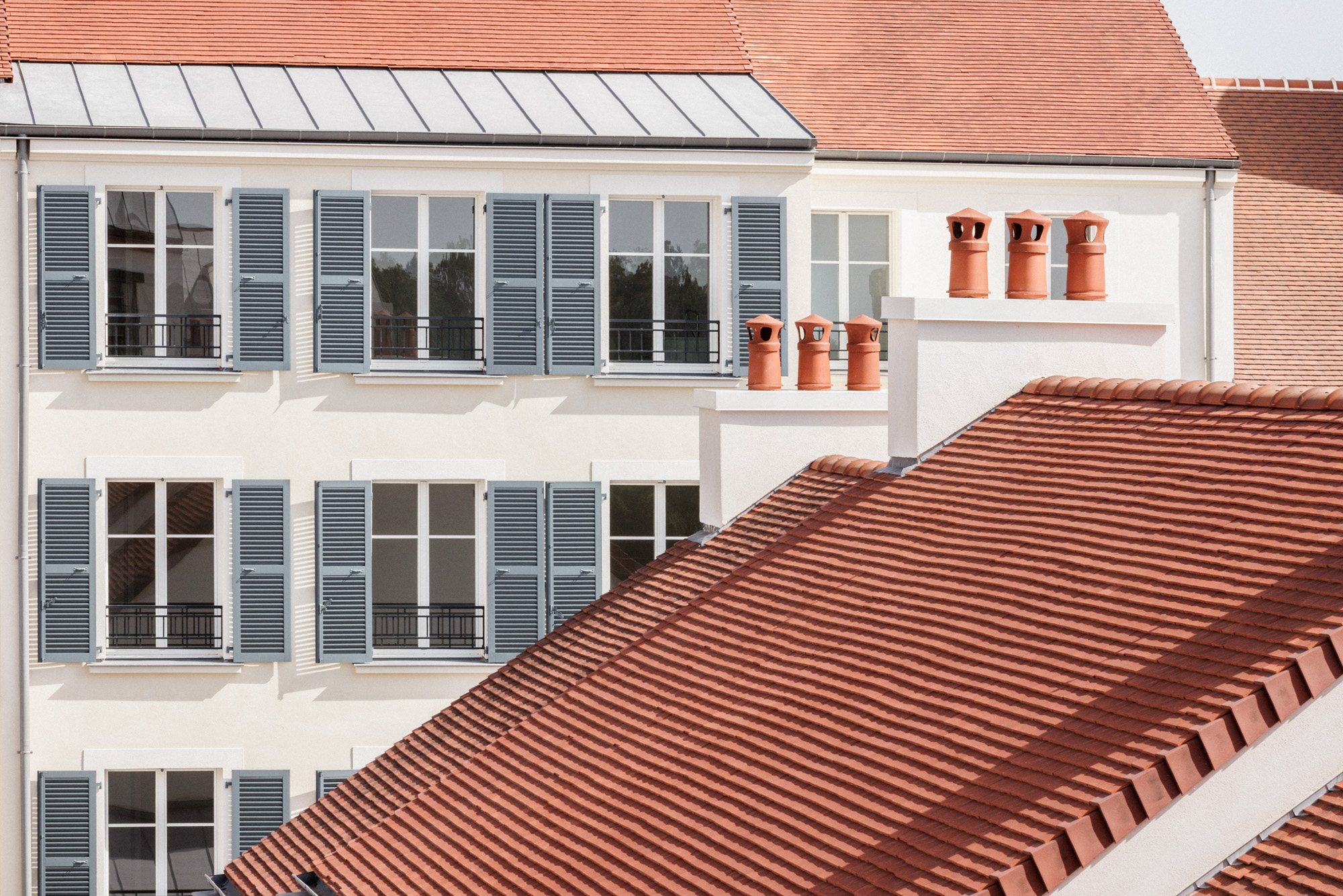 Vue des toitures en brique, volets en bois et cheminées du projet de logements sociaux "la cour des artisans" par Cussac Architectes et Associés (CA+A) à Serris.